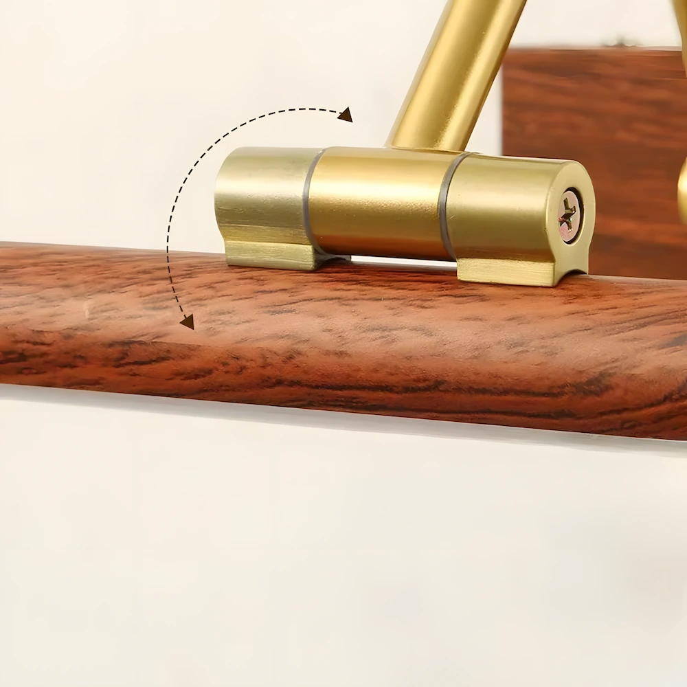 Close-up of brass picture light adjustable hinge mechanism on wood grain base showing 180-degree rotation capability