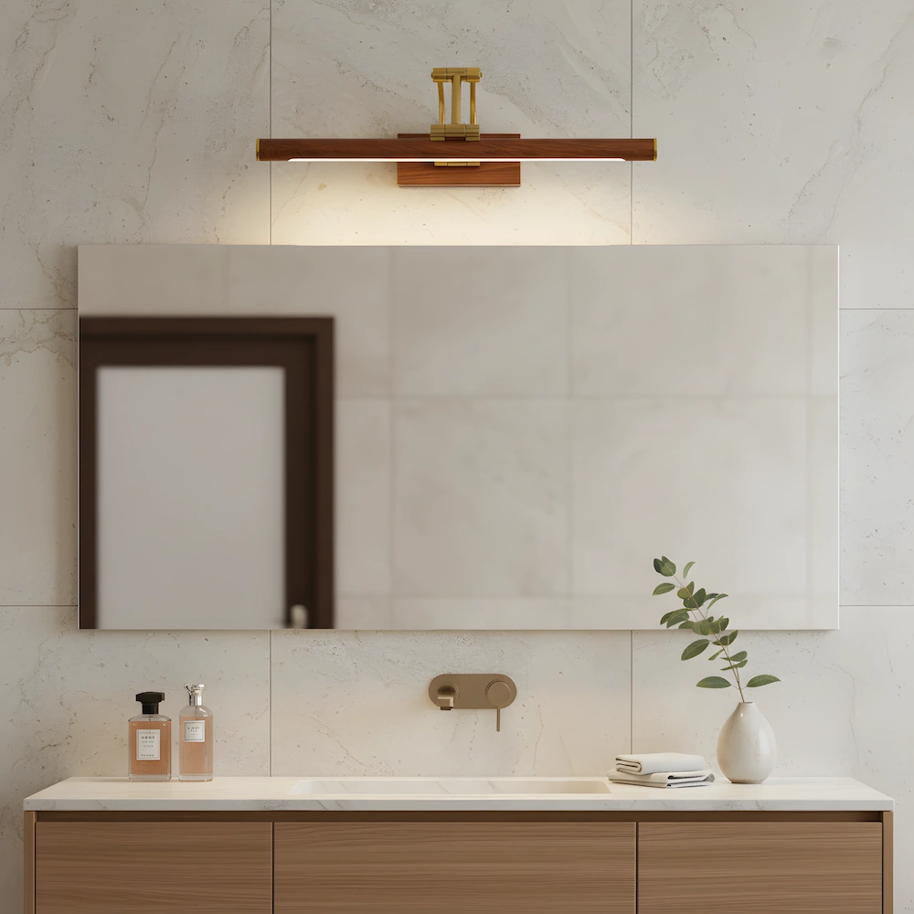 Brass picture light with natural wood grain base illuminating modern bathroom mirror with adjustable LED lighting